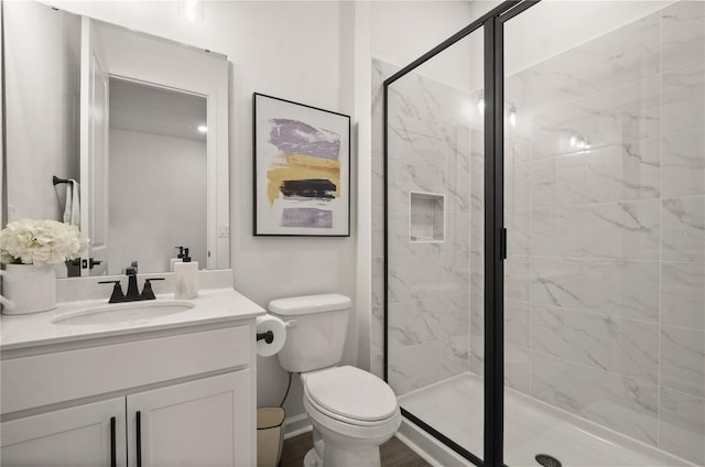 bathroom featuring a shower with door, vanity, and toilet