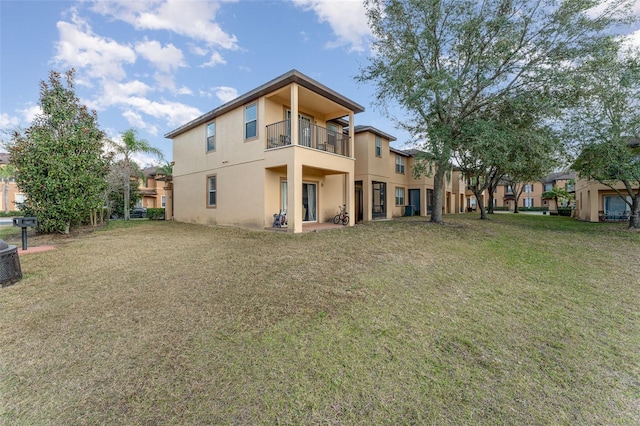 rear view of property with a balcony and a lawn