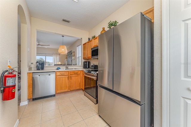 kitchen with sink, light tile patterned floors, ceiling fan, appliances with stainless steel finishes, and hanging light fixtures