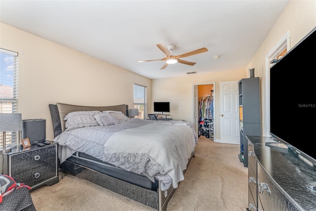 carpeted bedroom featuring ceiling fan, a walk in closet, and a closet