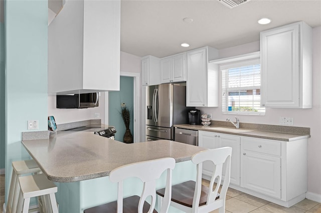 kitchen with sink, a breakfast bar area, appliances with stainless steel finishes, white cabinetry, and kitchen peninsula