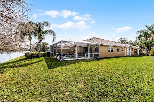 back of property with a water view, a yard, and a lanai
