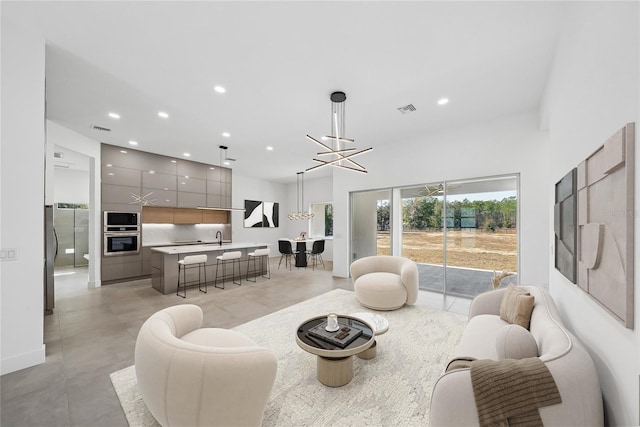 living room with a high ceiling, sink, and a chandelier