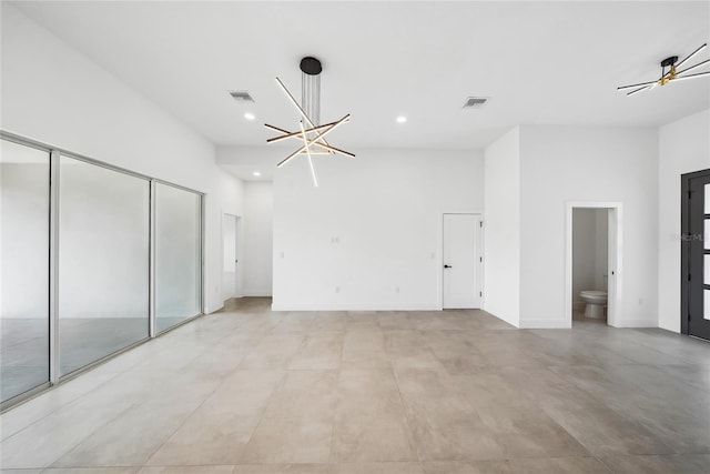 unfurnished bedroom featuring ensuite bathroom, a towering ceiling, and a chandelier