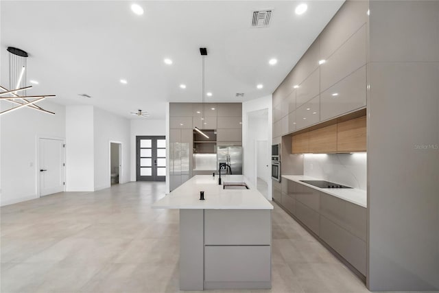 kitchen with pendant lighting, a spacious island, sink, stainless steel appliances, and french doors