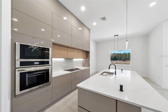 kitchen featuring sink, light stone counters, black appliances, an island with sink, and decorative light fixtures