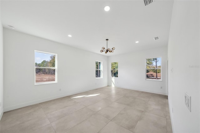 empty room featuring a notable chandelier and a wealth of natural light