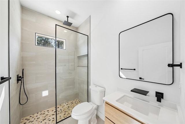 bathroom featuring vanity, toilet, and tiled shower