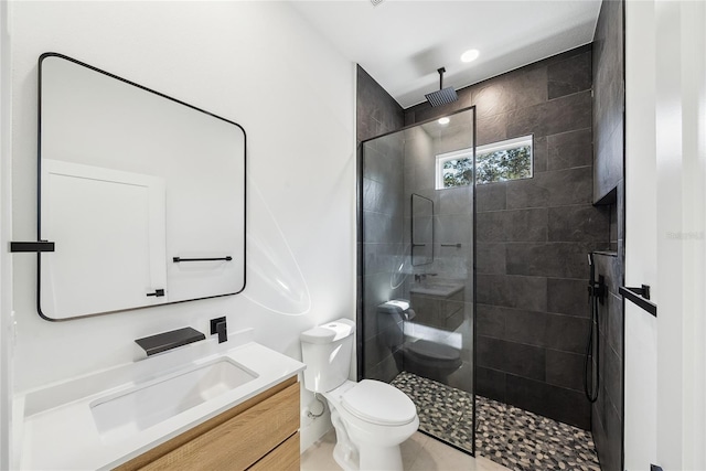 bathroom with vanity, toilet, and tiled shower