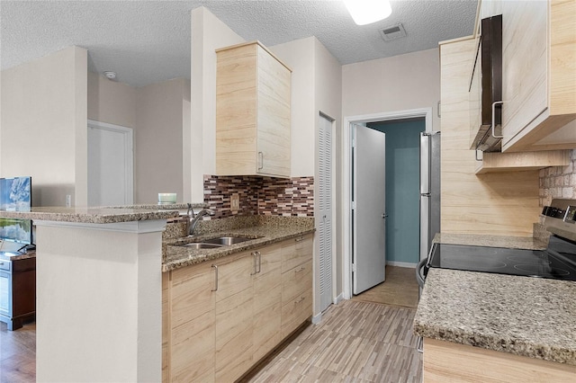 kitchen with sink, light brown cabinetry, light stone counters, and stainless steel range with electric stovetop