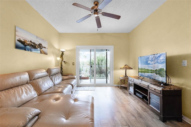 living room with ceiling fan, a textured ceiling, and light wood-type flooring