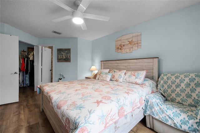 bedroom with ceiling fan, wood-type flooring, a textured ceiling, a spacious closet, and a closet