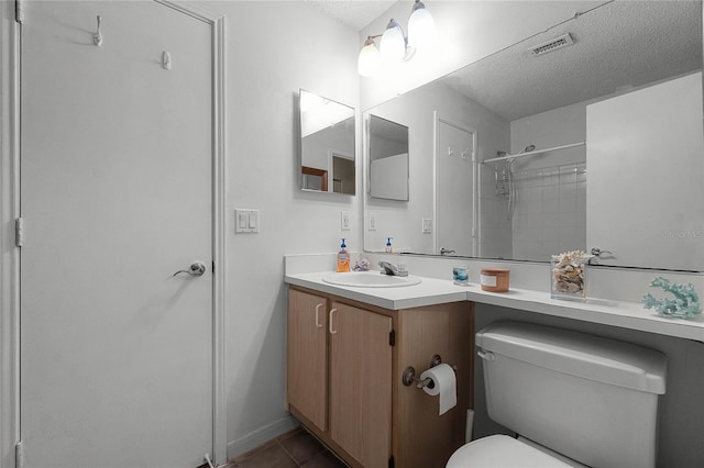 bathroom featuring vanity, tiled shower, toilet, tile patterned floors, and a textured ceiling