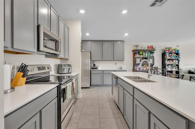 kitchen with gray cabinets, light tile patterned flooring, appliances with stainless steel finishes, and sink