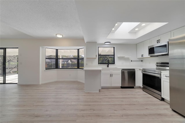 kitchen featuring sink, light hardwood / wood-style flooring, stainless steel appliances, a textured ceiling, and white cabinets