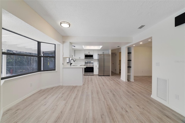 unfurnished living room with sink, a textured ceiling, and light wood-type flooring