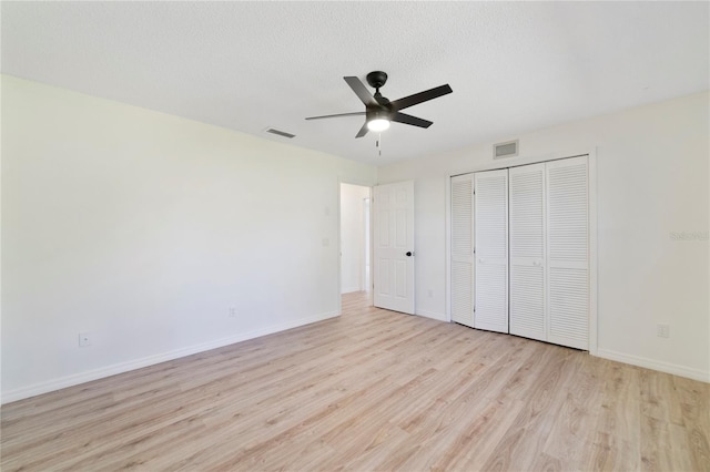 unfurnished bedroom featuring ceiling fan, a textured ceiling, light wood-type flooring, and a closet