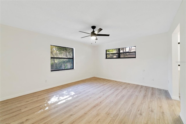 spare room with ceiling fan, plenty of natural light, and light wood-type flooring