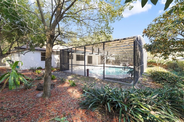 rear view of property featuring a patio area and glass enclosure