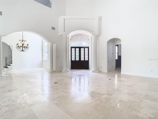 entrance foyer with an inviting chandelier, a high ceiling, a healthy amount of sunlight, and ornate columns