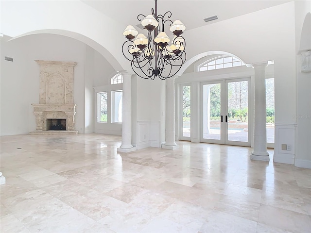 interior space with french doors, a high ceiling, and ornate columns