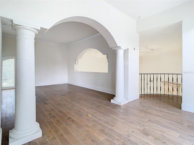 spare room with hardwood / wood-style floors and ornate columns