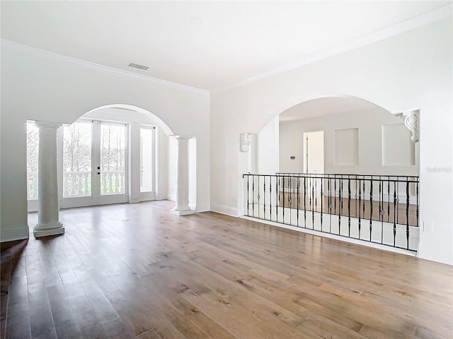 spare room featuring hardwood / wood-style flooring, ornamental molding, french doors, and ornate columns