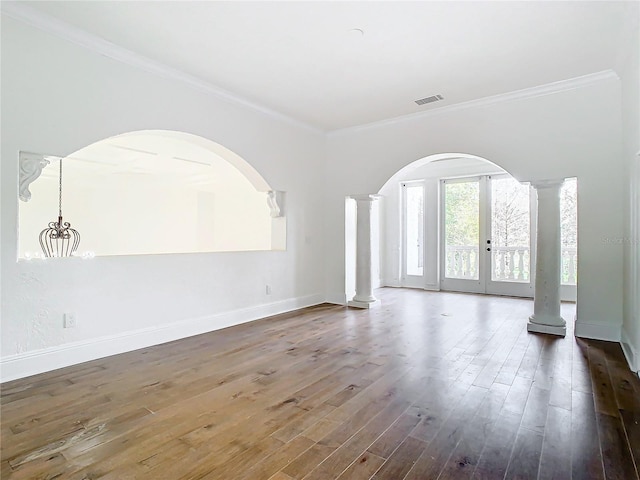 unfurnished living room with ornate columns, ornamental molding, dark hardwood / wood-style floors, and french doors