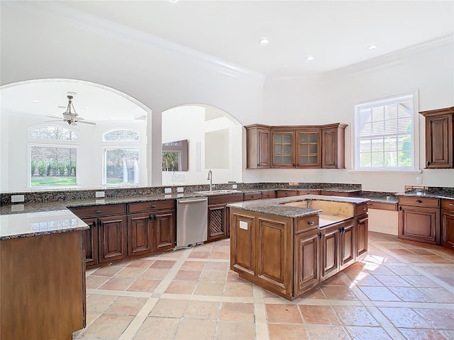 kitchen featuring sink, crown molding, stone countertops, stainless steel dishwasher, and a kitchen island