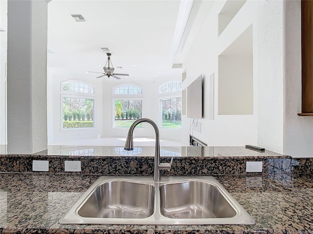 kitchen with dark stone countertops, sink, and ceiling fan