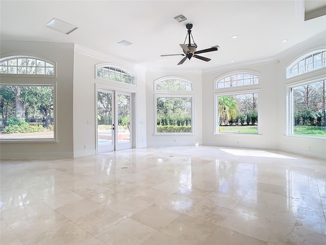 empty room with crown molding, a healthy amount of sunlight, ceiling fan, and french doors