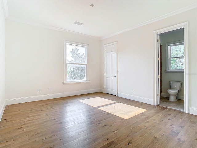 unfurnished bedroom featuring connected bathroom, ornamental molding, and light wood-type flooring