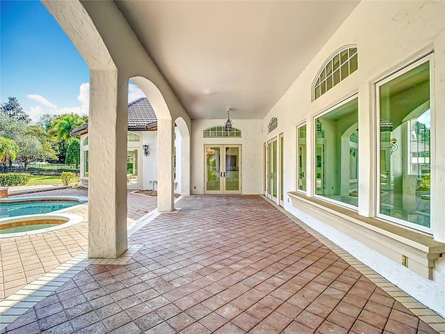 view of patio / terrace with french doors, ceiling fan, and an in ground hot tub