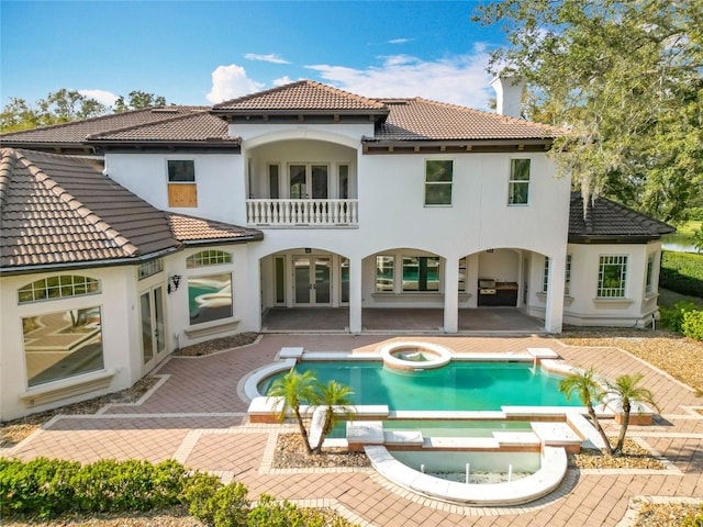 rear view of property featuring a patio area and an in ground hot tub