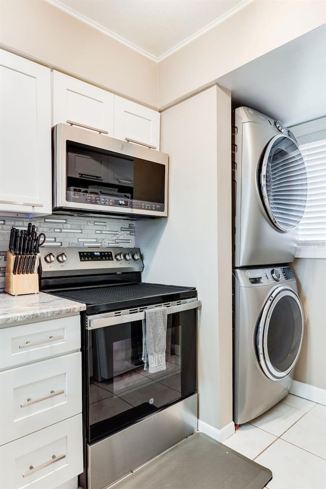 kitchen featuring stacked washer / drying machine, tasteful backsplash, ornamental molding, stainless steel appliances, and white cabinets