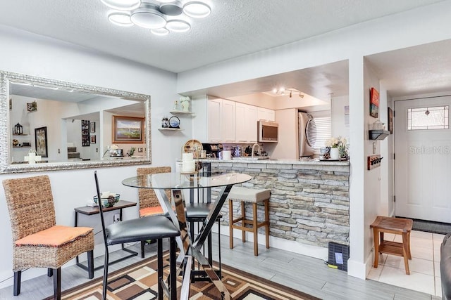 kitchen with white cabinetry, kitchen peninsula, a textured ceiling, and light hardwood / wood-style flooring