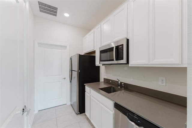 kitchen with stainless steel appliances, white cabinetry, sink, and light tile patterned flooring