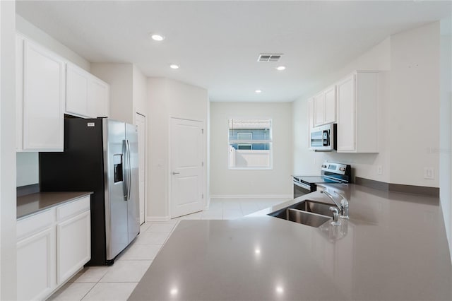 kitchen featuring stainless steel appliances, sink, light tile patterned floors, and white cabinets