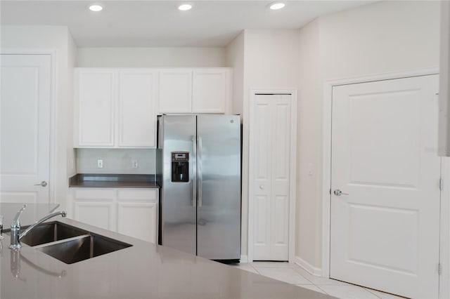 kitchen featuring white cabinetry, stainless steel fridge, light tile patterned flooring, and sink