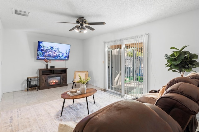 living room featuring ceiling fan, light tile patterned flooring, and a textured ceiling