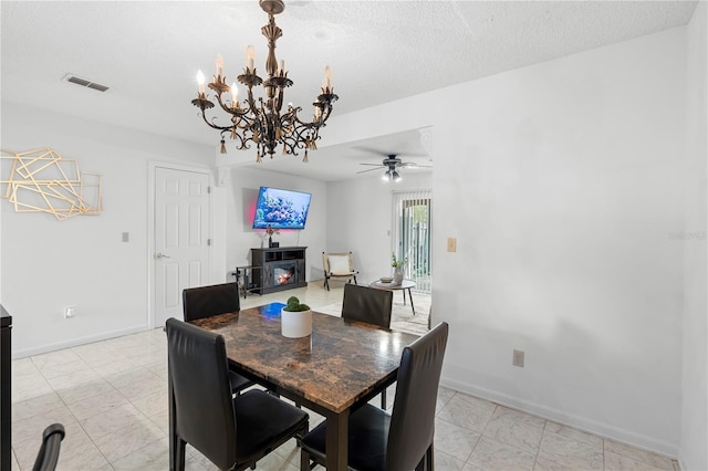 dining space with ceiling fan with notable chandelier and a textured ceiling