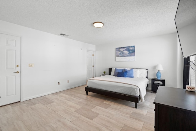 bedroom with light wood-type flooring and a textured ceiling
