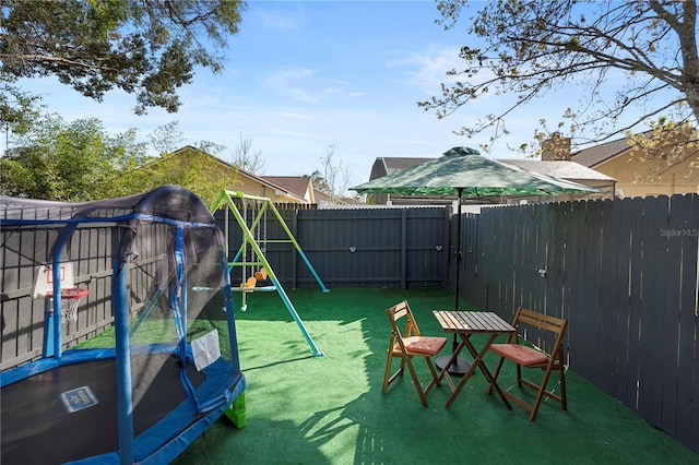 view of jungle gym with a trampoline and a lawn