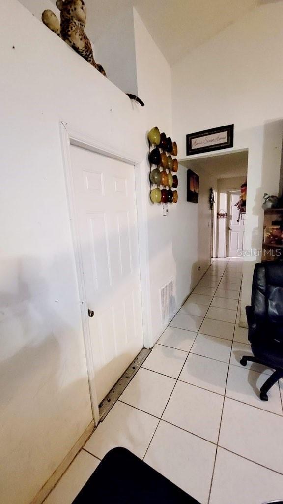 1417 Brookebridge Dr, Orlando, FL 32825 - hallway with light tile patterned floors, visible vents, and high vaulted ceiling