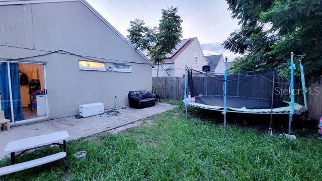 1417 Brookebridge Dr, Orlando, FL 32825 - view of yard with a trampoline, fence, and a patio