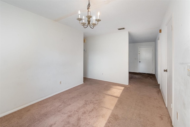 spare room with light carpet and an inviting chandelier