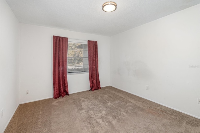 empty room with light colored carpet and a textured ceiling