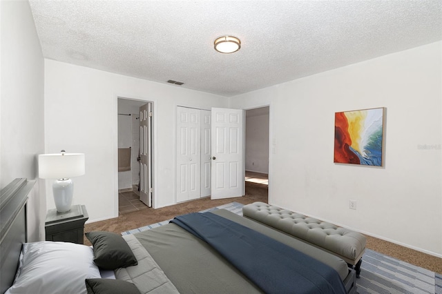 carpeted bedroom featuring ensuite bath, a closet, and a textured ceiling