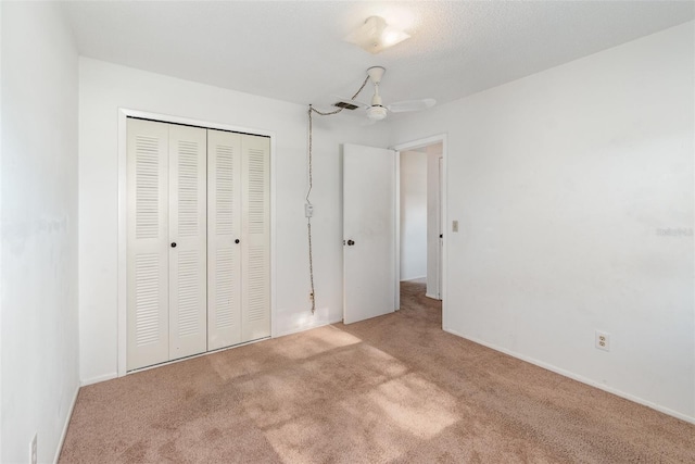 unfurnished bedroom with light colored carpet, a closet, and a textured ceiling