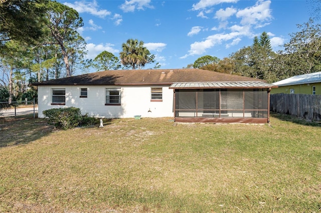 rear view of house featuring a yard and a sunroom